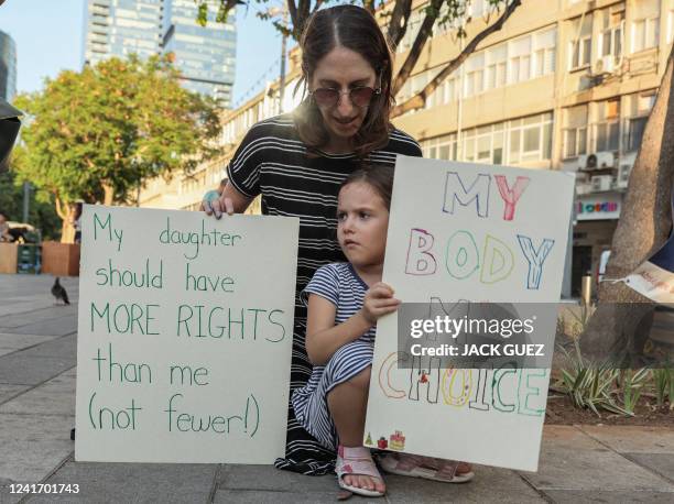 Woman sits with a girl while both hold up signs reading in English "my daughtyer should have more rights than me " and "my body my choice" during a...