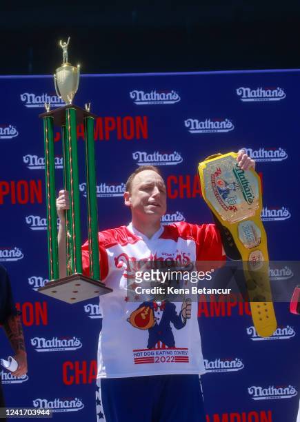 Joey Chestnut holds the trophy and belt after he won first place, eating 63 hot dogs in 10 minutes, during the 2022 Nathan's Famous Fourth of July...