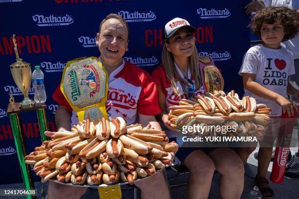 Joey Chestnut and Miki Sudo hold 63 and 40 hot dogs respectively after winning the Nathan's Famous 4th of July 2022 hot dog eating contest on Coney...
