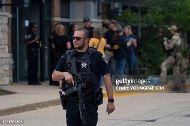 Police officer searches the scene of the Fourth of July parade shooting in Highland Park, Illinois on July 4, 2022. - A shooter opened fire Monday...