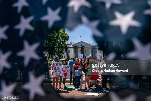 Abortion-rights activists are seen though a ripped American Flag during a rally in front of the White House on July 4, 2022 in Washington, DC....