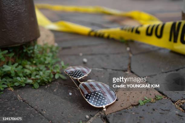 Police crime tape is seen near an American flag-themed sunglasses laying on the ground at the scene of the Fourth of July parade shooting in Highland...