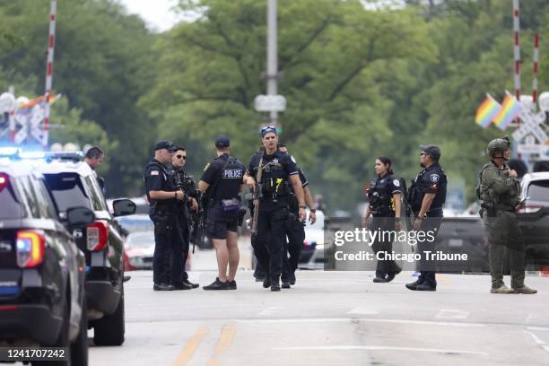 Law enforcement officials work the scene along the Highland Park Fourth of July parade route after people fled the scene on July 4 after a shooter...