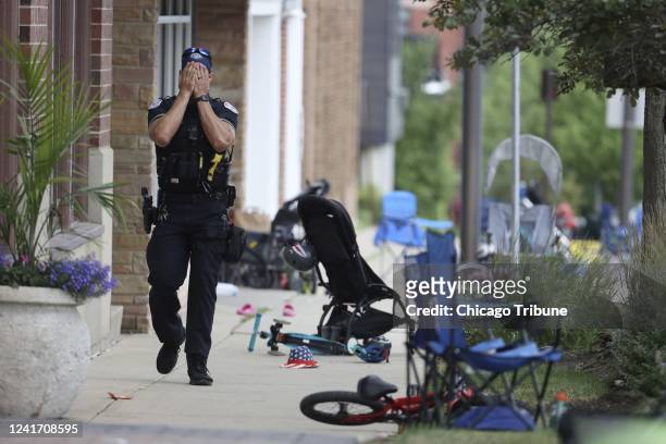 Lake County, Illinois, police officer walks down Central Avenue in Highland Park on July 4 after a shooter fired on the northern suburb&apos;s Fourth...