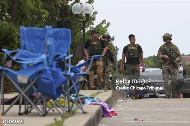Law enforcement officers from multiple jurisdictions investigate the area in Highland Park, Illinois, on Monday, July 4 after a shooter fired on the...