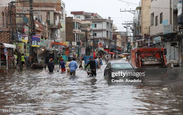 Pakistani people struggle to move forward in a flooded street after heavy monsoon rain in Rawalpindi, Pakistan, on July 05, 2022. Rescue workers said...