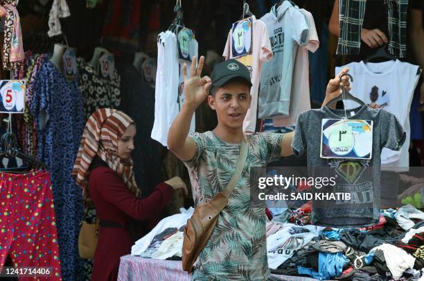 Palestinian man carries a t-shirt at a shop at a market in Khan Yunis, in the southern Gaza Strip on July 5 as Muslims prepare for the Eid al-Adha...