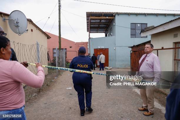 South African Police Services members use a tape to cordon off the entrance of a township pub in southern city of East London on July 5 after the...