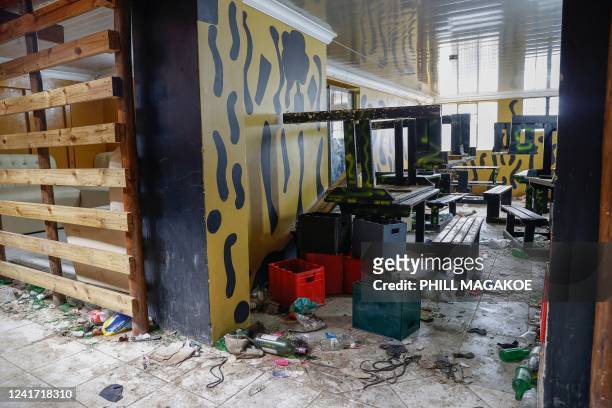 Empty alcohol bottles, crates, wooden chairs and tables are seen inside a township pub in southern city of East London on July 5 after the death of...