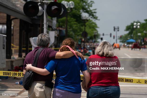 Family embraces while observing the scene of a mass shooting at a July 4th Parade in downtown Highland Park, Illinois on July 5, 2022. - The...