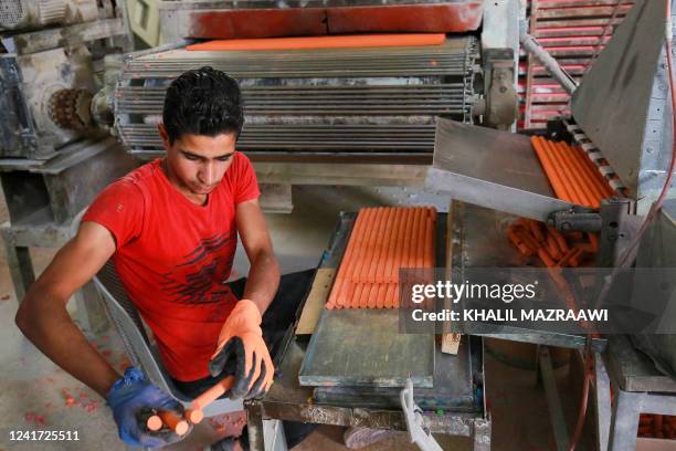 Worker puts coloured chalk through a machine at the Jordan Chalk company in Karak, around 120 kilometres south of the capital Amman on June 13, 2022....