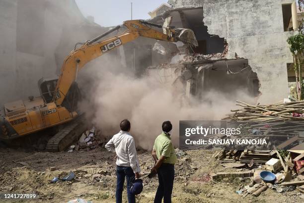 In this file photo taken on June 12 a bulldozer demolishes the house of Javed Mohammad, a local leader who was allegedly involved in the recent...