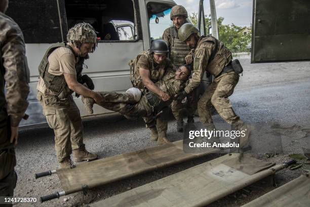 Ukrainian servicemen evacuate a wounded soldier from the battlefield into an ambulance during heavy shelling in Siversk, Ukraine on July 05, 2022.