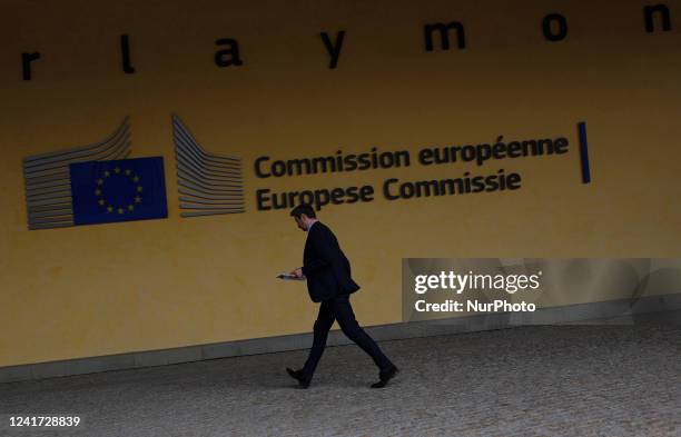 Man hurries to work as he walks past the logo of the European Union outside the EU headquarters in Brussels. Belgium, Wednesday, July 6th, 2022.