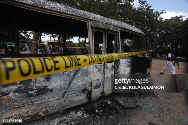 Police officer walks beside a burnt prison vehicle in Abuja, Nigeria on July 6 after suspected Boko Haram gunmen attacked the Kuje Medium Prison....