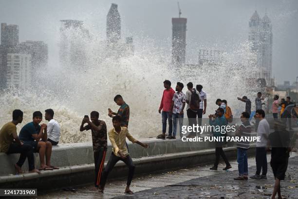 People enjoy high tides splashing on the sea front during rain showers in Mumbai on July 6, 2022.