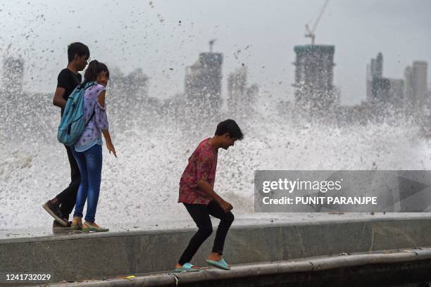 People enjoy high tides splashing on the sea front during rain showers in Mumbai on July 6, 2022.