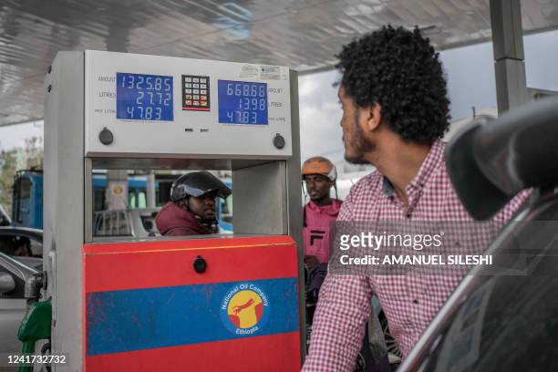 Man looks at the new fuel price as he fills his car at a fuel station in Addis Ababa, Ethiopia, on July 6, 2022. - Fuel prices soared in Ethiopia on...
