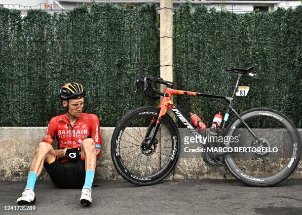 Bahrain Victorious team's Australian rider Jack Haig rests on the sidewalk next to his bicycle after a fall during the 5th stage of the 109th edition...