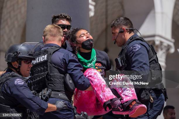 Police arrest four women protesters who chained themselves to the columns at the steps of City Hall to denounce the U.S. Supreme Court decision to...