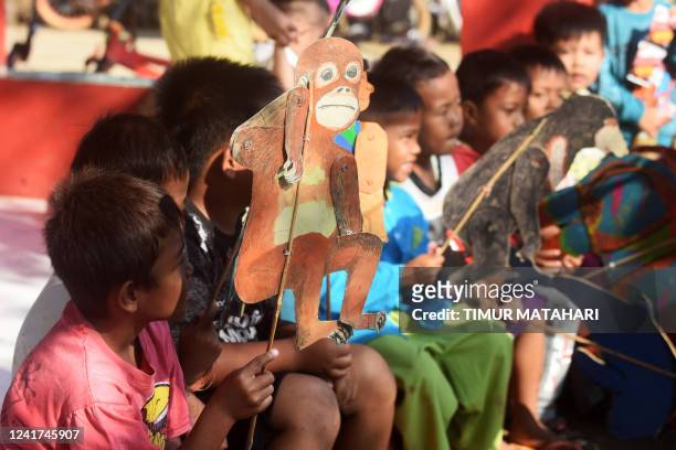 This picture taken on June 19, 2022 shows children watching former teacher Samsudin while he teaches them about animal conservation with cardboard...