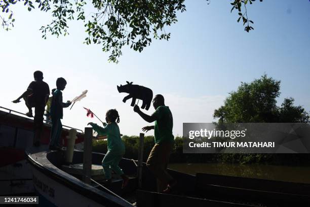 This picture taken on June 19, 2022 shows former teacher Samsudin teaching children about animal conservation with cardboard puppets at Cemara Kulon...