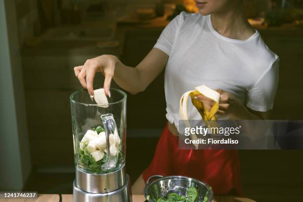 woman preparing smoothie - banana woman photos et images de collection