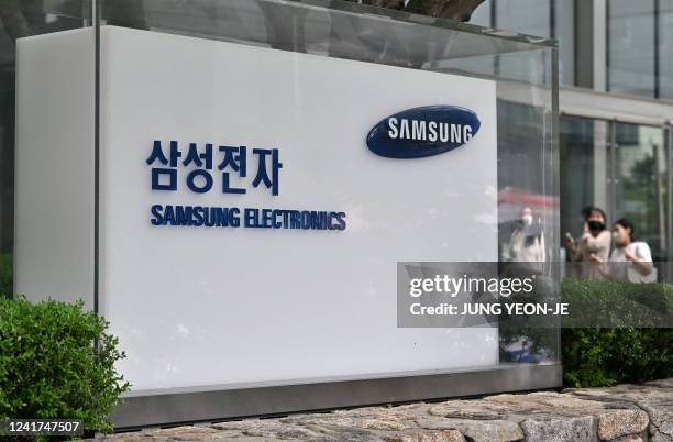 People walk past the logo of Samsung Electronics outside the company's Seocho building in Seoul on July 7, 2022.