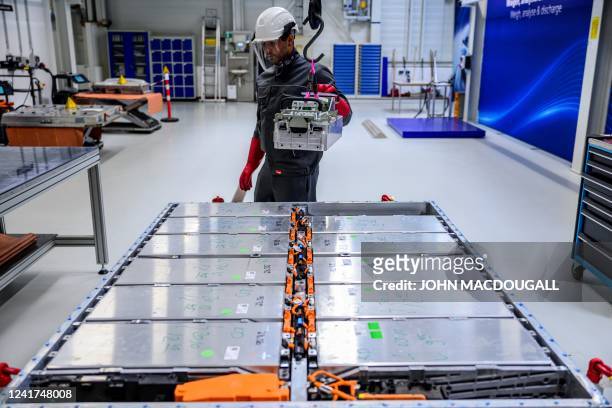 Worker removes a module, containing the battery cells, from a battery pack at Volkswagen's pilot recycling plant for car battery cells at the VW...