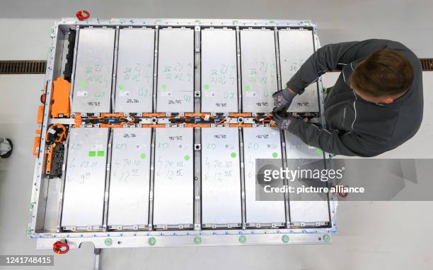 May 2022, Lower Saxony, Salzgitter: An employee removes battery modules from a worn-out battery of an electric car in battery recycling at the VW...