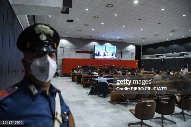 Family members of victims sit in a courtroom as they follow on a screen the first hearing of the Morandi bridge collapse trial at the courthouse of...