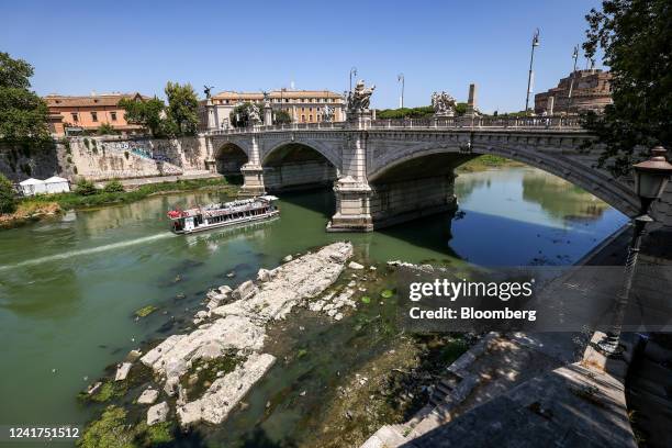 Sightseeing tourist boat sails past the resurfaced remains of an ancient bridge built under Roman Emperor Nero in the River Tiber, following...