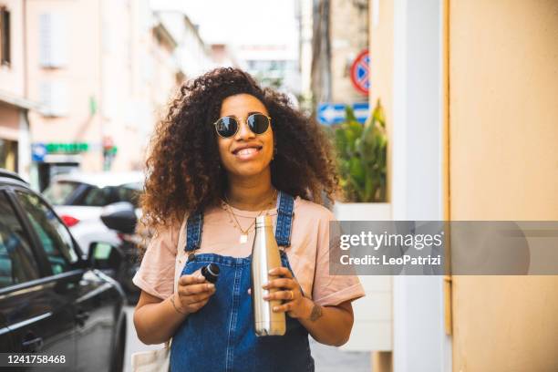 portrait of a smiling afro hair woman holding a reusable water bottle - reusable stock pictures, royalty-free photos & images
