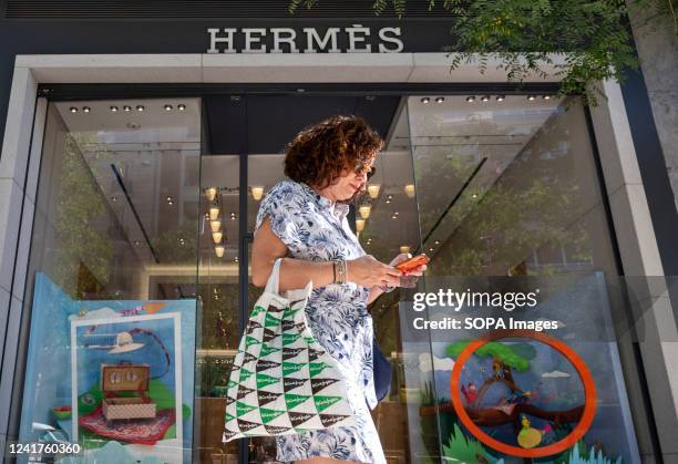 Pedestrian walks past the French high fashion luxury clothing manufacturer Hermes store in Spain.