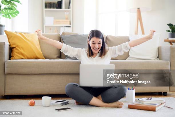 young woman with laptop expressing excitement in home office, quarantine concept. - eccitazione foto e immagini stock
