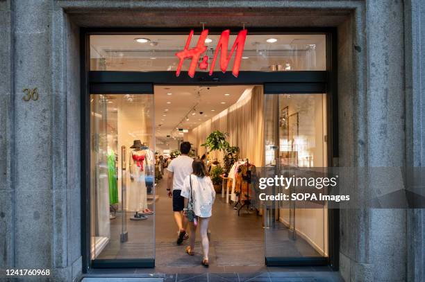 Shoppers walk into the Swedish multinational clothing design retail company Hennes & Mauritz, H&M store in Spain.