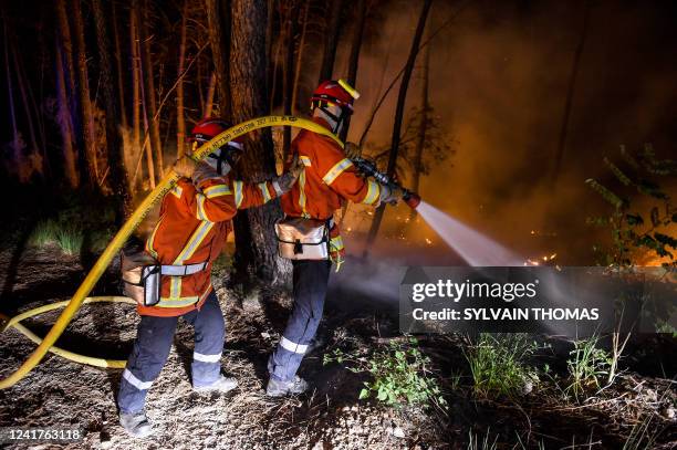 Firefighters spray water to extinguish a wildfire near Besseges, southern France, on July 7, 2022.