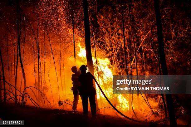 Firefighters spray water to extinguish a wildfire near Besseges, southern France, on July 7, 2022.