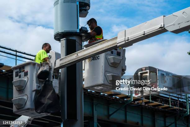 Workers install a Link5G-transmitting smart pole which sits atop of a LinkNYC kiosk on July 7, 2022 in The Bronx borough of New York City. The...