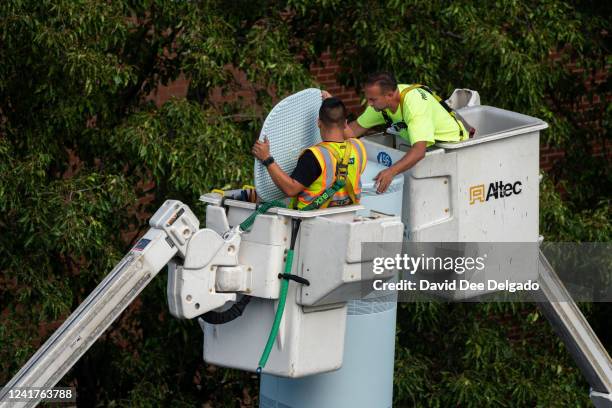 Workers install a Link5G-transmitting smart pole which sits atop of a LinkNYC kiosk on July 7, 2022 in The Bronx borough of New York City. The...