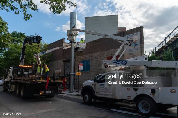 Workers install a Link5G-transmitting smart pole which sits atop of a LinkNYC kiosk on July 7, 2022 in The Bronx borough of New York City. The...
