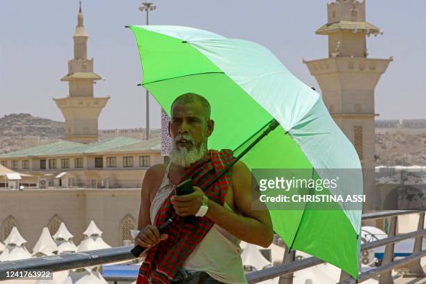 Muslim pilgrim walks with an umbrella at the camp in Mina near the Saudi holy city of Mecca on July 7, 2022 during the annual Hajj pilgrimage.