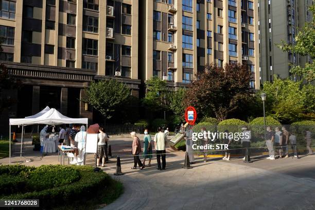 Residents queue to undergo nucleic acid tests for the Covid-19 coronavirus in Xi'an in China's central Shaanxi province on July 8, 2022. - China OUT...