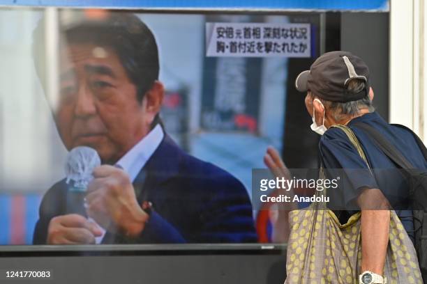 An old man watches TV news information on the street about Shinzo Abe, former Prime Minister of Japan, who was shot from during a street meeting as...