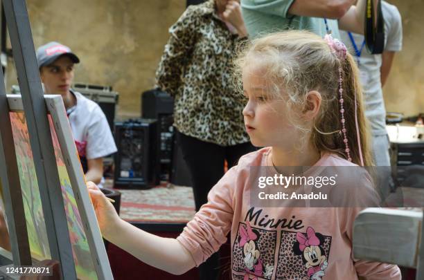Children who lost their homes and families due to Russian attacks paint pictures for a charity auction in Sligo during the action "War Through the...