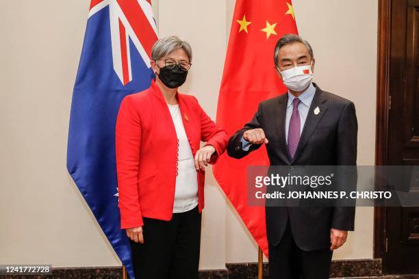 Australia's Foreign Minister Penny Wong bumps elbows with China's Foreign Minister Wang Yi during their bilateral meeting on the sidelines of G20...