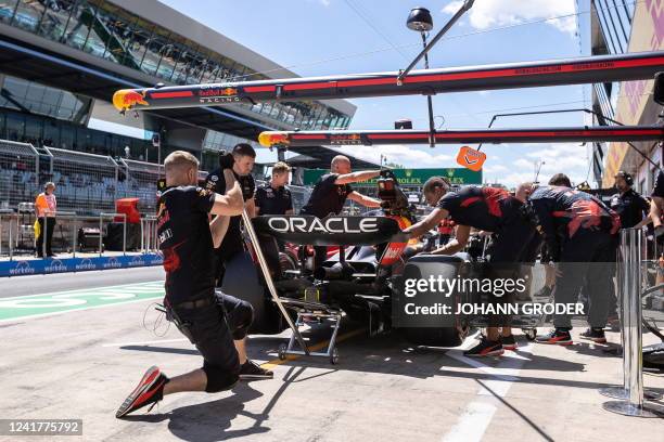 Mechanics works on the car of Red Bull Racing's Mexican driver Sergio Perez in the pits during the first practice session at the Red Bull Ring race...