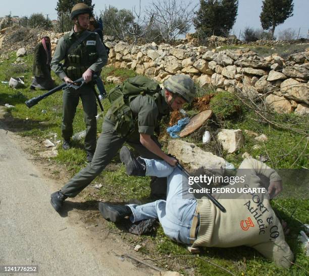 An Israeli border policeman hits a resident of the northern West Bank town of Beit Surik, on the edge of Jerusalem, with a baton as protesters tried...