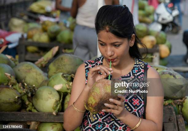 Woman drinking coconut water at a street stall during a hot summer day, in Guwahati, Assam, India on Friday, 8 July 2022. Severe heat conditions have...