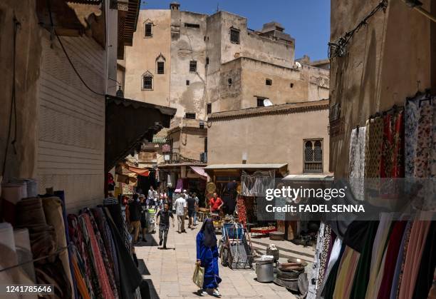 People walk down a street in the ancient Moroccan city of Fez on June 8, 2022. - Today, Fez serves as a monument to a highpoint of Islamic...